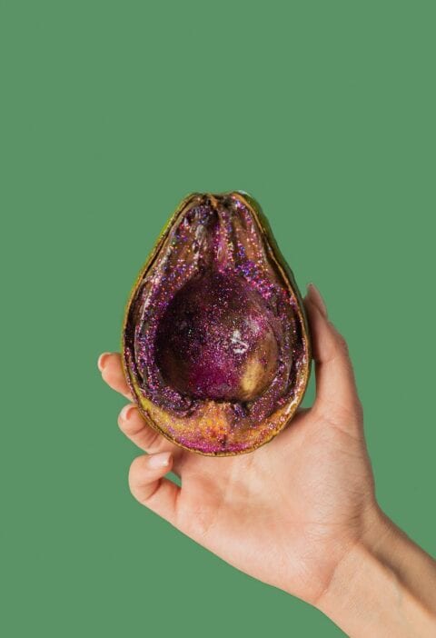 female showing half avocado with pink glitter