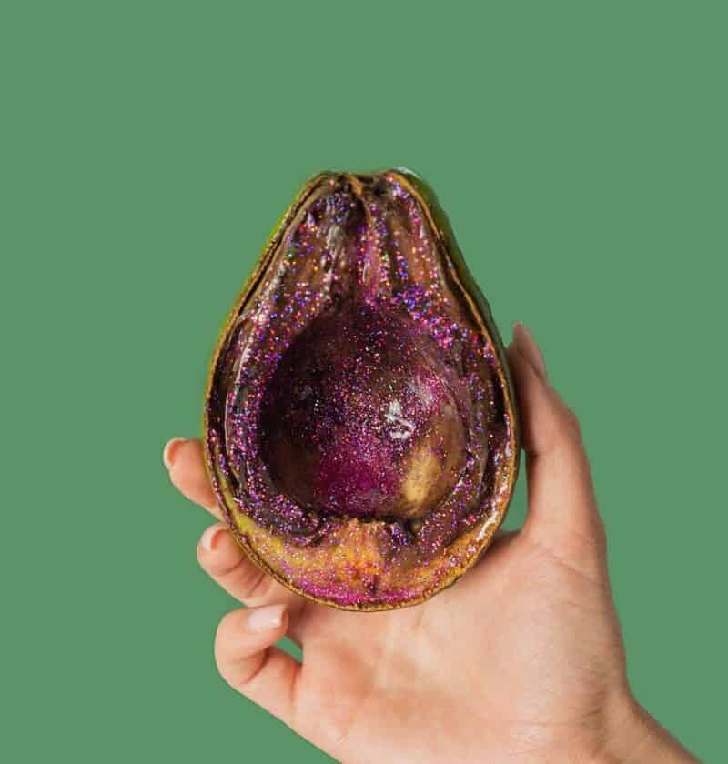 female showing half avocado with pink glitter