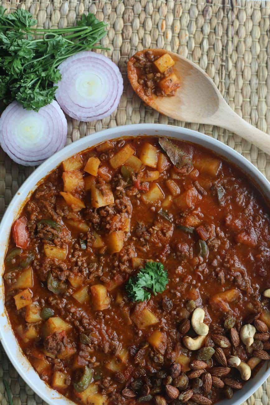 cooked food in a bowl beside a wooden spoon